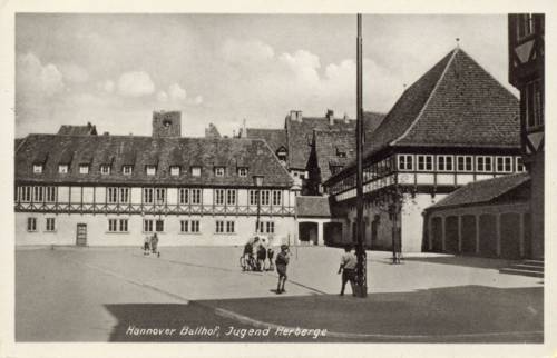 Foto-Postkarte: Ballhofplatz. Die Postkarte zeigt eine Fotografie des Ballhofplatzes mit Blickrichtung Nordost. Die Dächer im Hintergund lassen darauf schließen, dass die Aufnahme vor der Zerstörung im 2. Weltkrieg getätigt wurde. 1938-1945